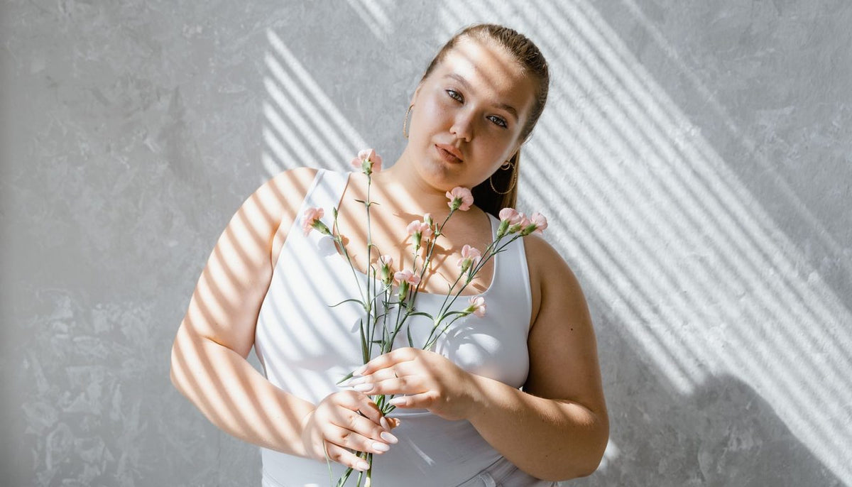 Femme en robe claire posant près d'un mur lumineux, coupe fluide et bretelles larges Image