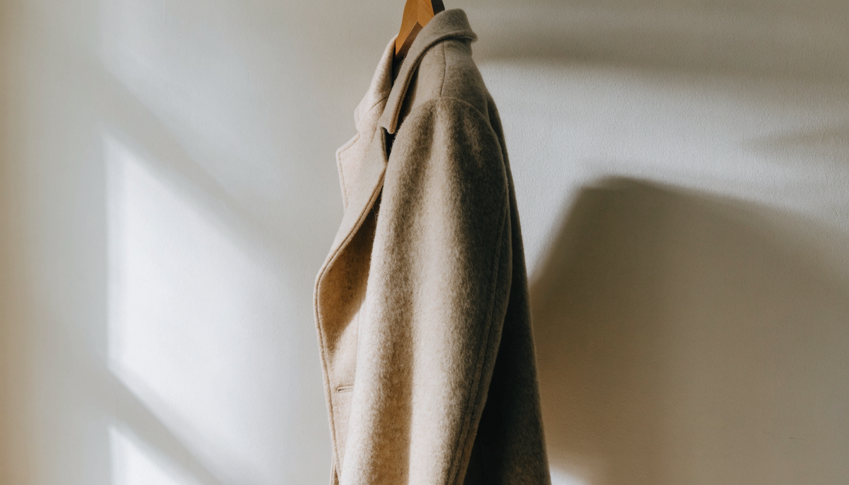 Manteau long grande taille suspendu près d'une fenêtre, coupe droite visible