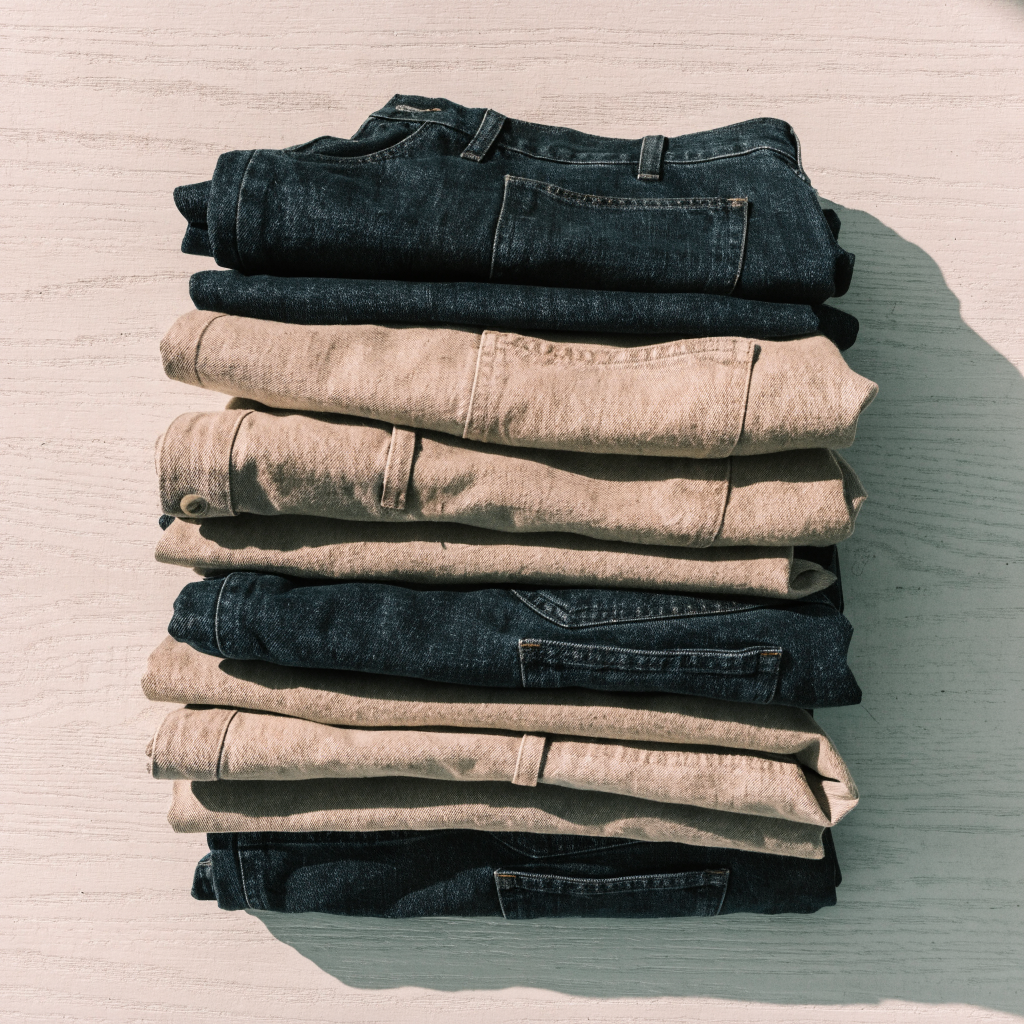 Pantalons et jeans pliés empilés sur un plan en bois clair